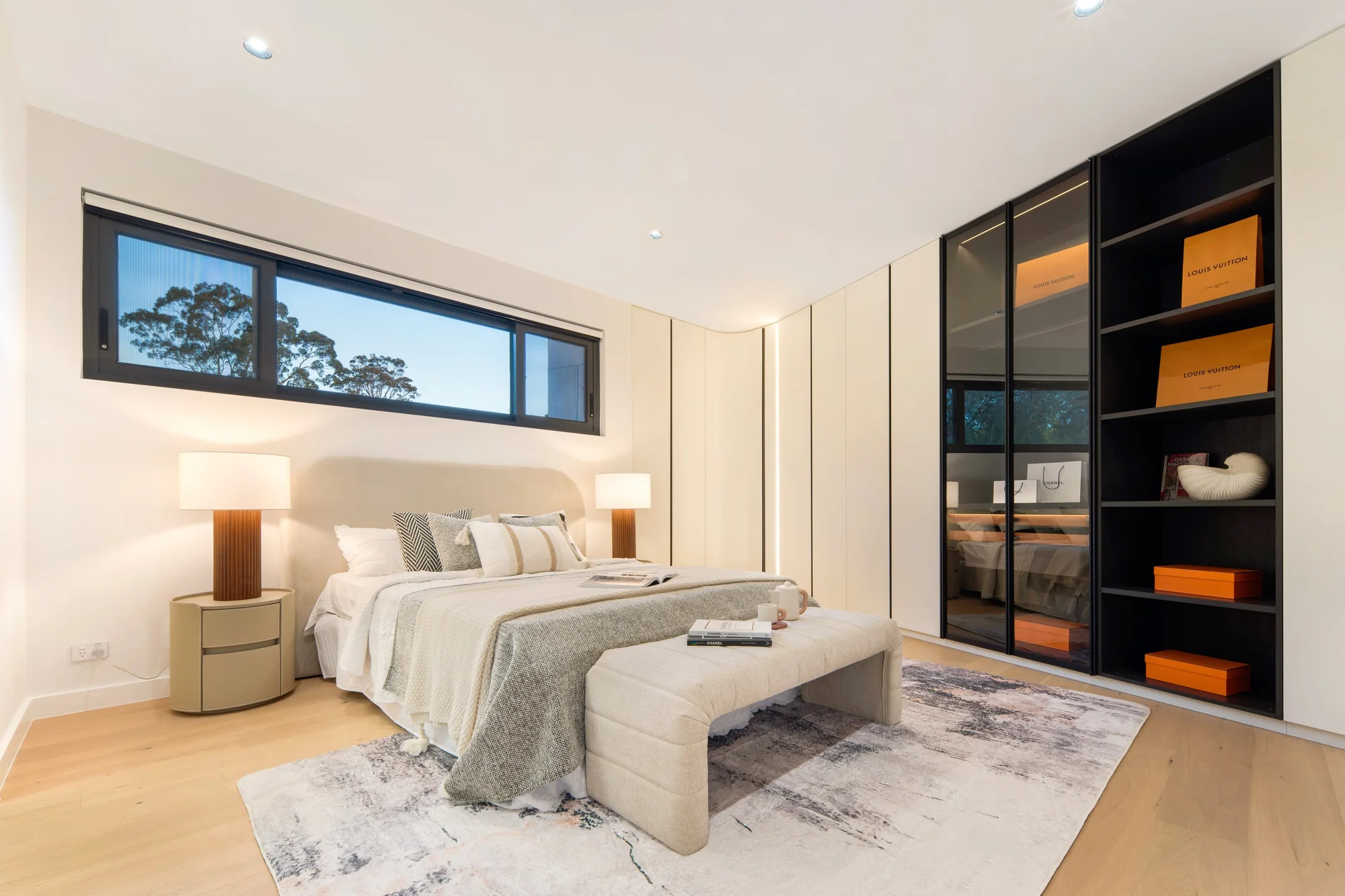 Bedroom with a high horizontal window and full-height fitted wardrobes