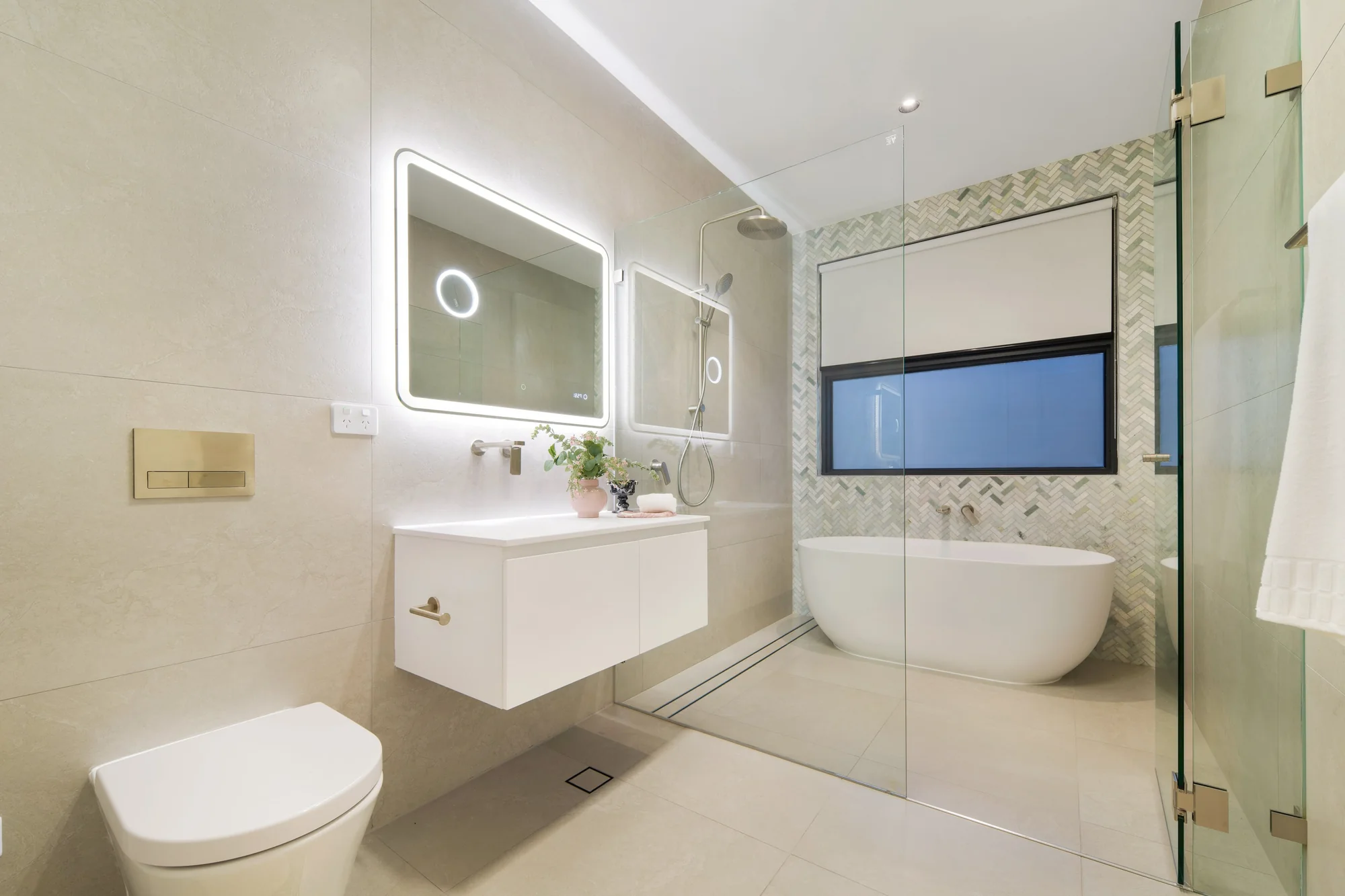 Bathroom with a freestanding bath, glass shower and illuminated mirror
